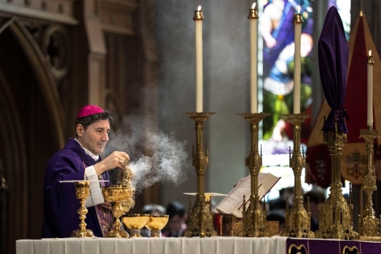 An archbishop stands at an alter holding mass.