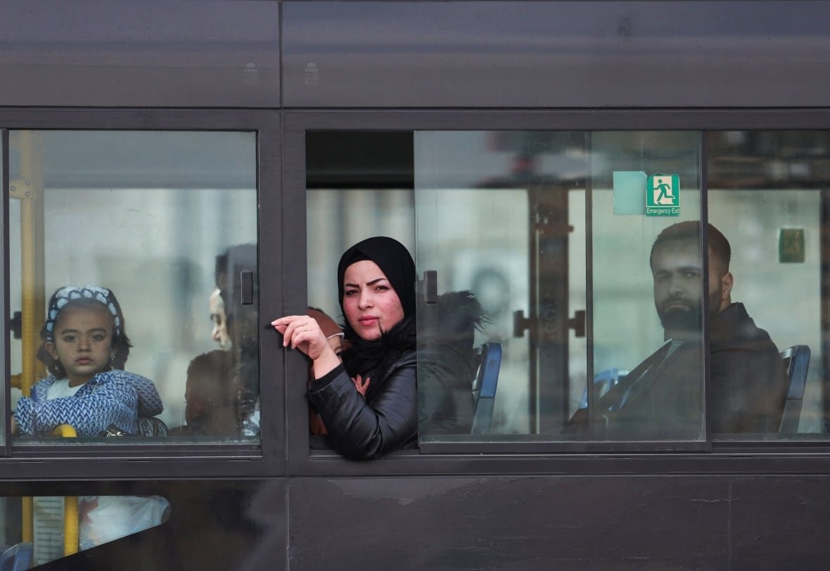 People sitting in a bus look out the window.