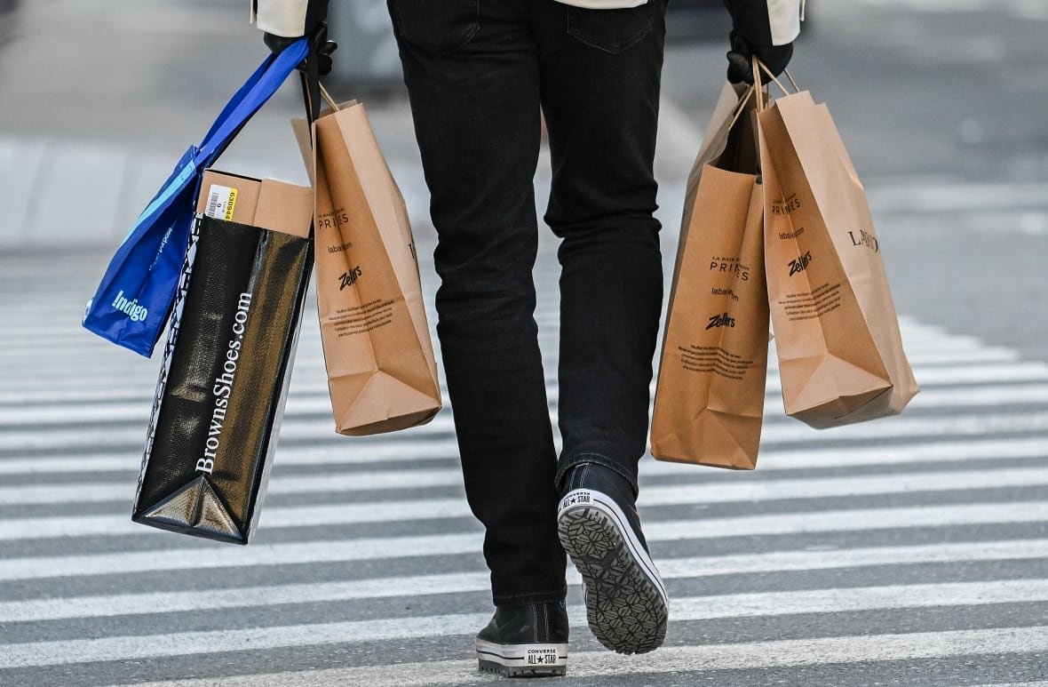 A person carries shopping bags along a street.