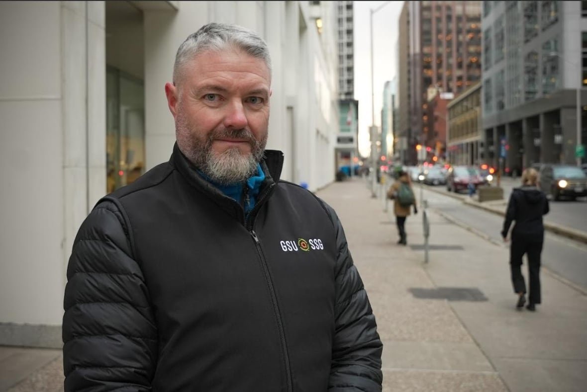 a man standing outside on a sidewalk. 
