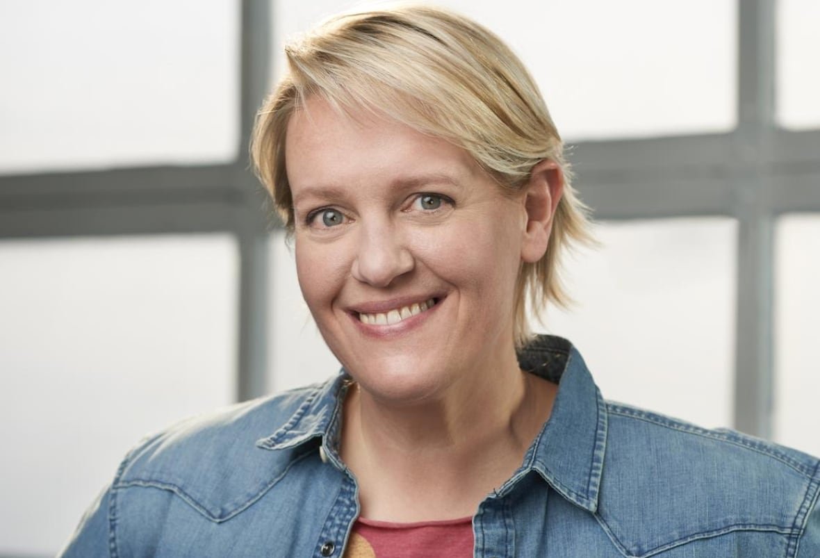 A woman with blond hair wears a blue jean jacket.