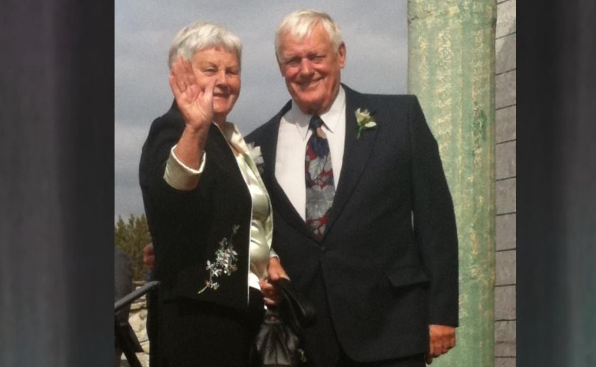 A picture of an older man in a suit beside a woman in a dress.