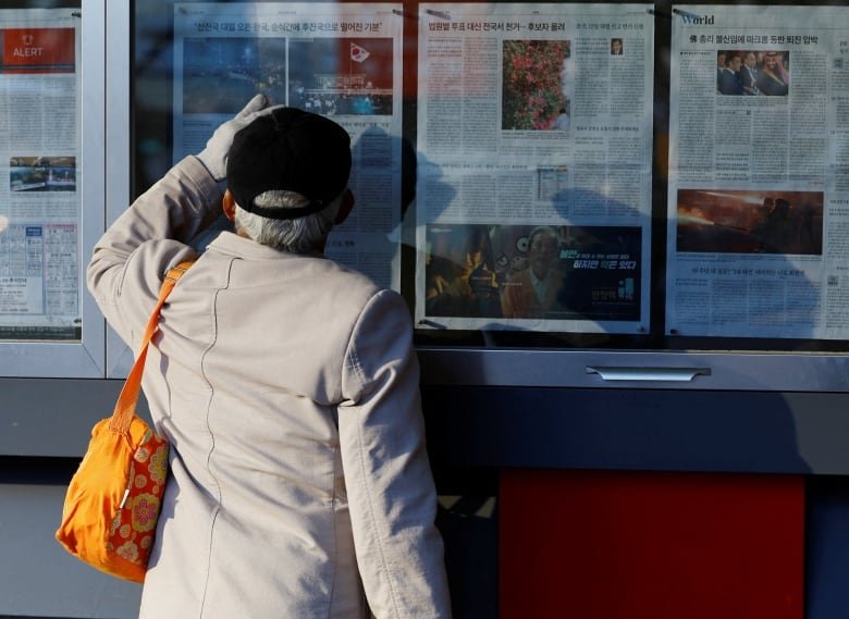 A man in Seoul, South Korea, reads news reports about South Korean President Yoon Suk Yeol's failed martial law attempt.