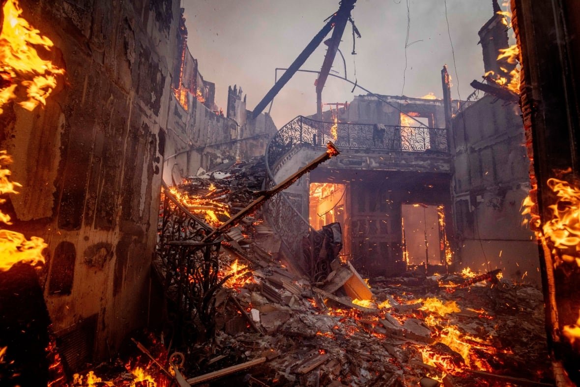 A large homes burns revealing a charred winding staircase.