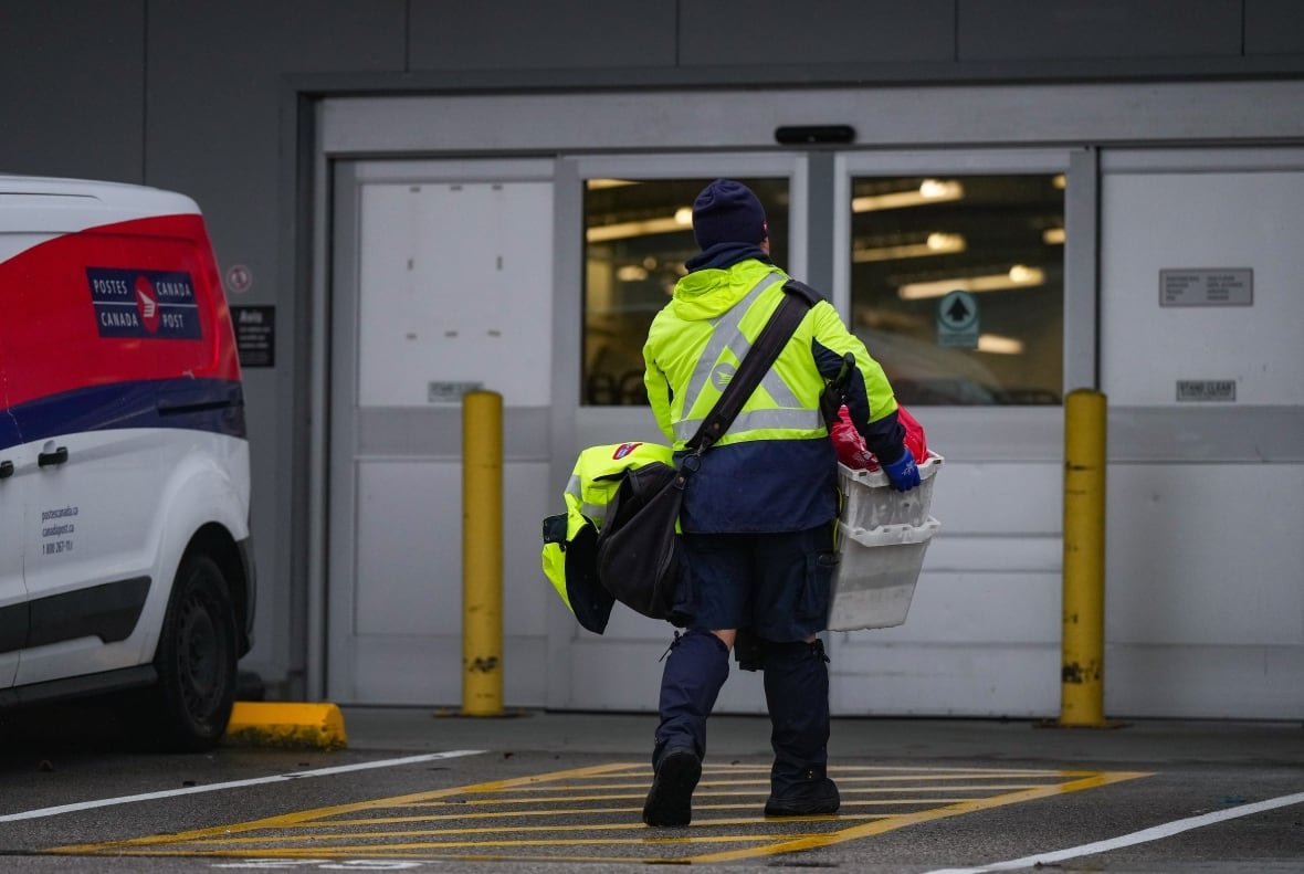 A mail carrier holds a bin of mail