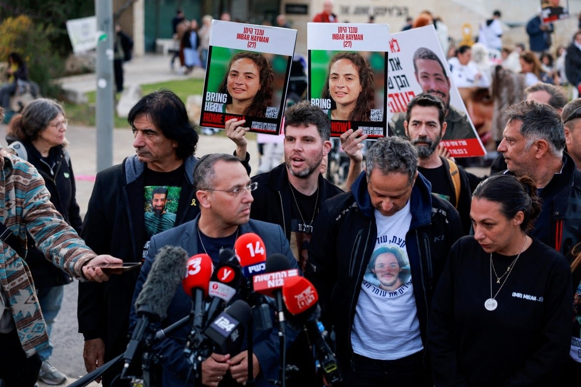 Men and women at the front of a protest gather at a set of microphones. 
