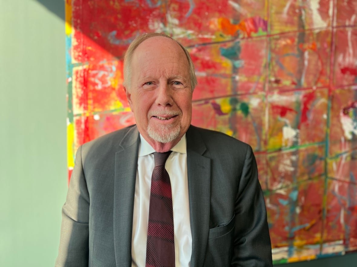 A portrait of Steven Bookman in front of a painting in his Toronto office.