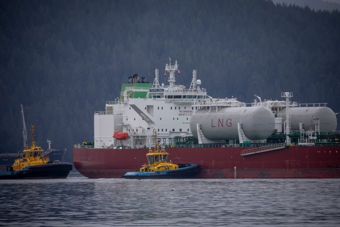 An oil tanker and tugboats are seen in the ocean.