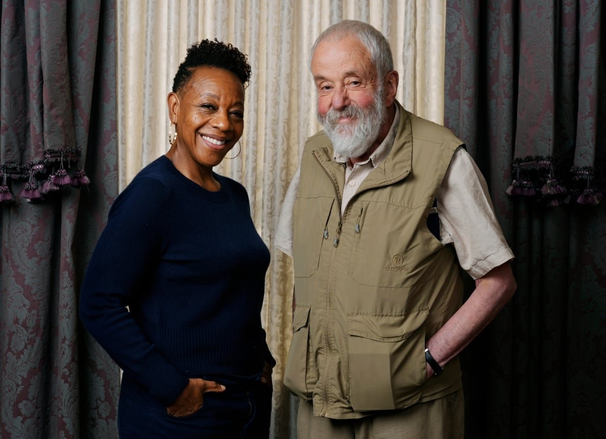 A woman and older man smile at the camera.