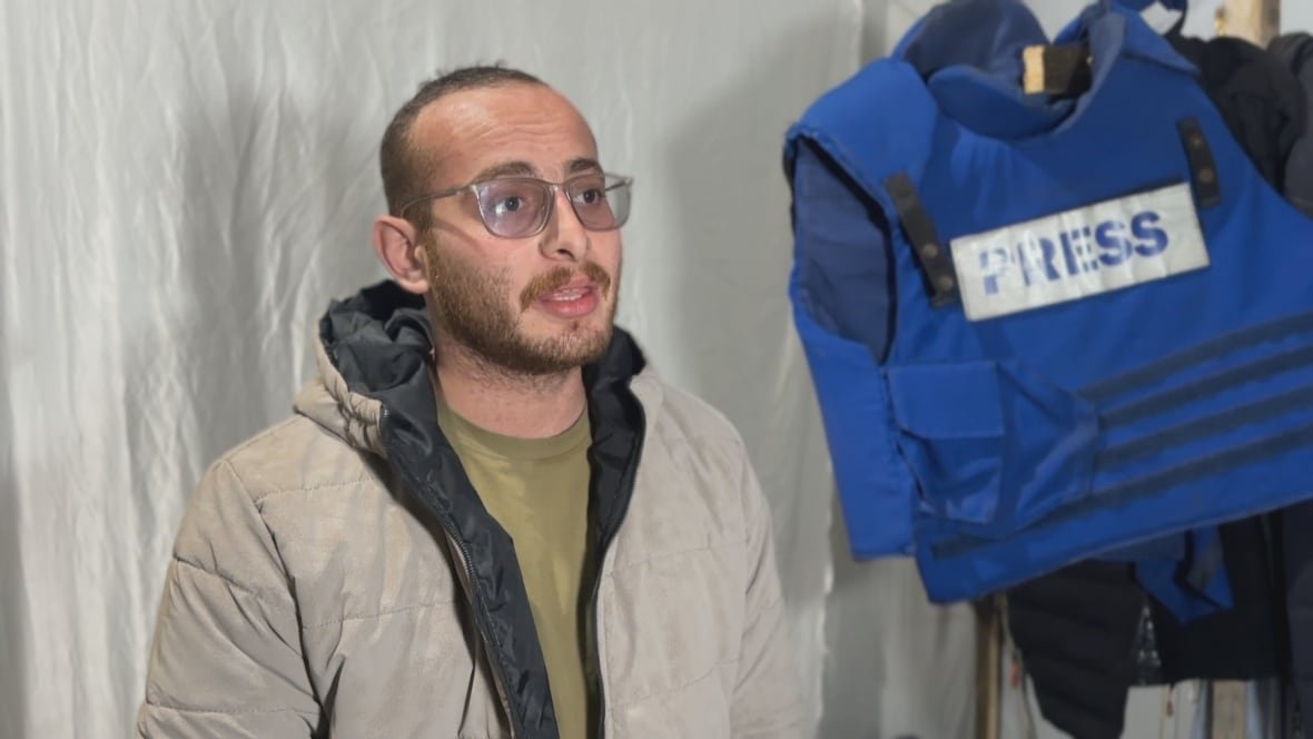 a man in a beige coat stands in a tent