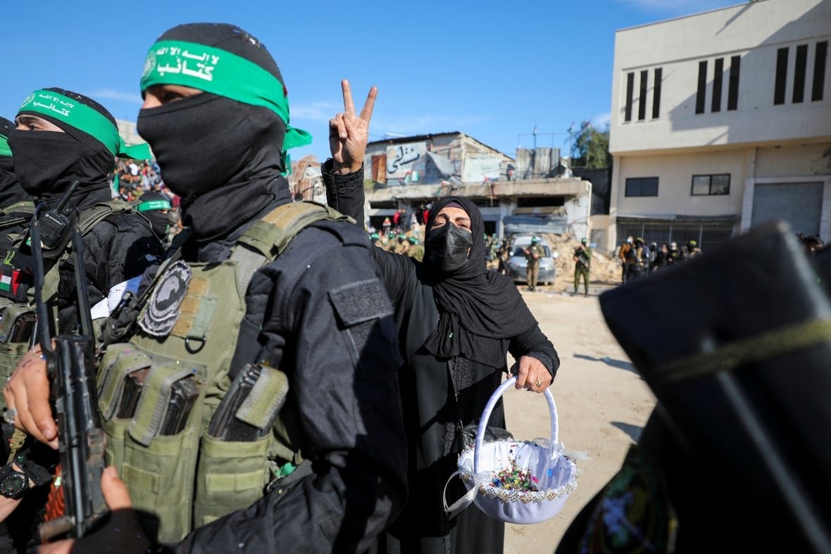 A Palestinian woman gestures as she greets Hamas militants on the day they release four female Israeli soldiers, who had been held in Gaza since the deadly October 7, 2023 attack, as part of a ceasefire and a hostages-prisoners swap deal between Hamas and Israel, in Gaza City, January 25, 2025. 