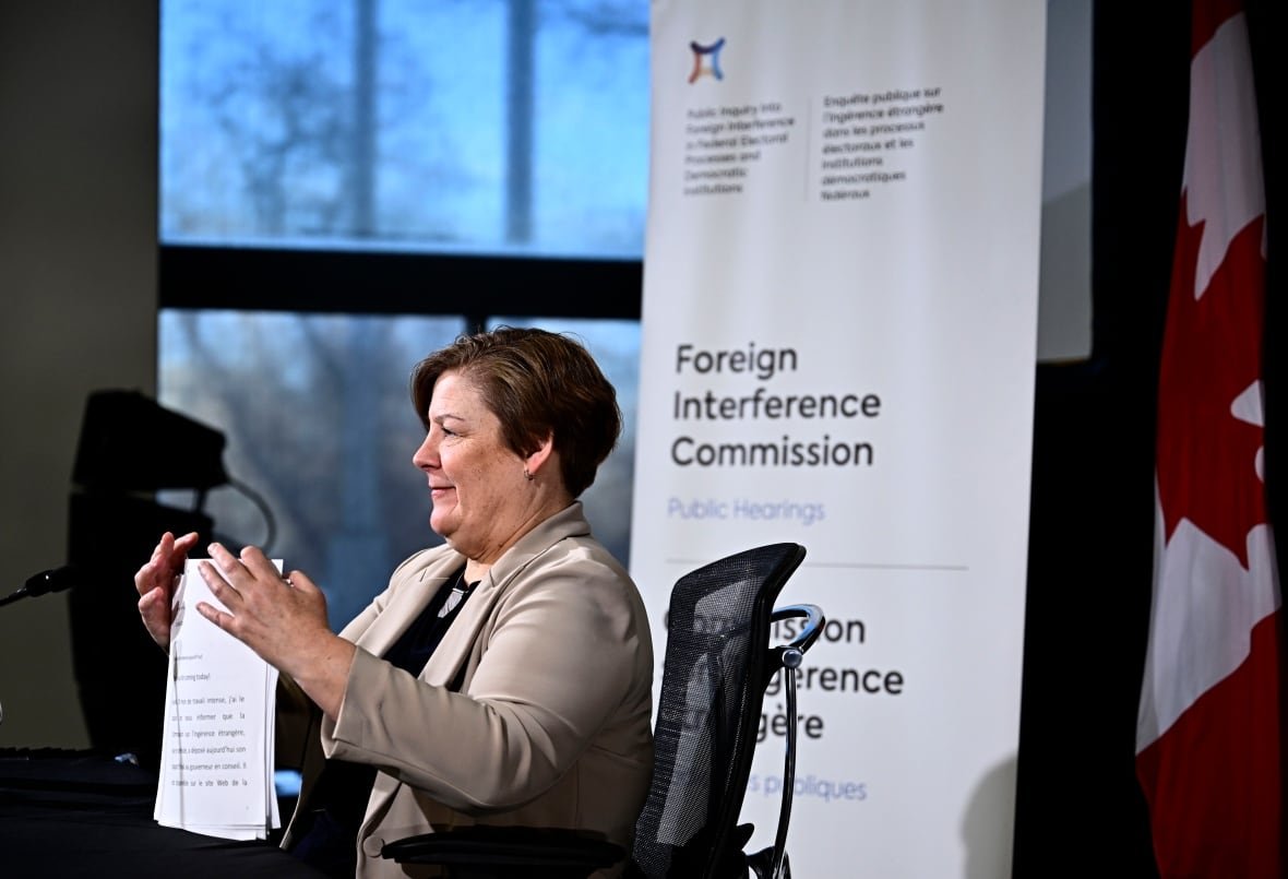 A woman shuffles paper at a desk.