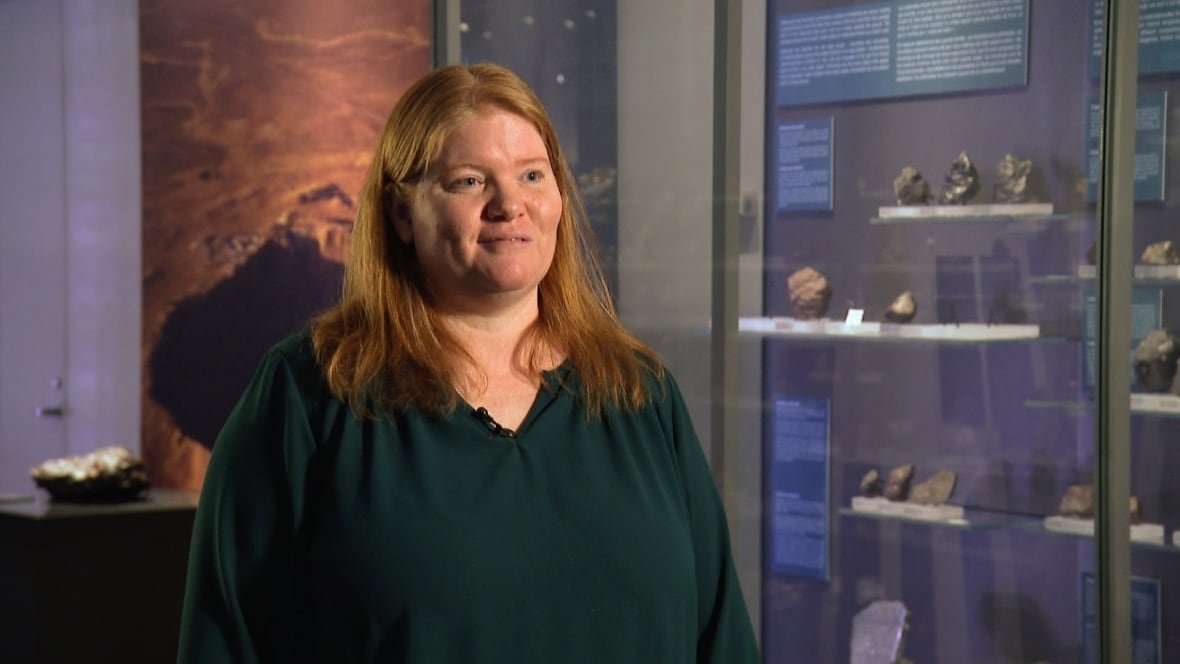 Woman with a museum case full of rocks in the background