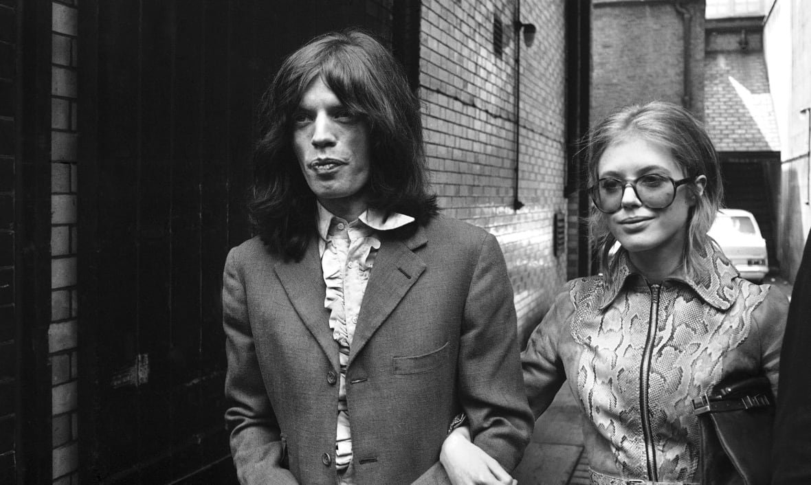 A man and a woman walk arm in arm in this black and white photo. 