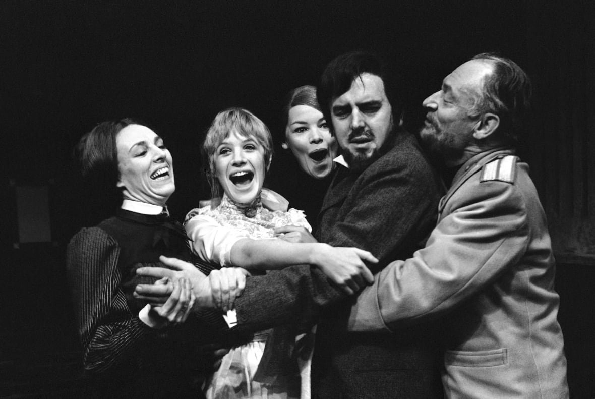 A group of people are all embracing and clustered together, in various stages of emotion, some excited, others looking confused. 