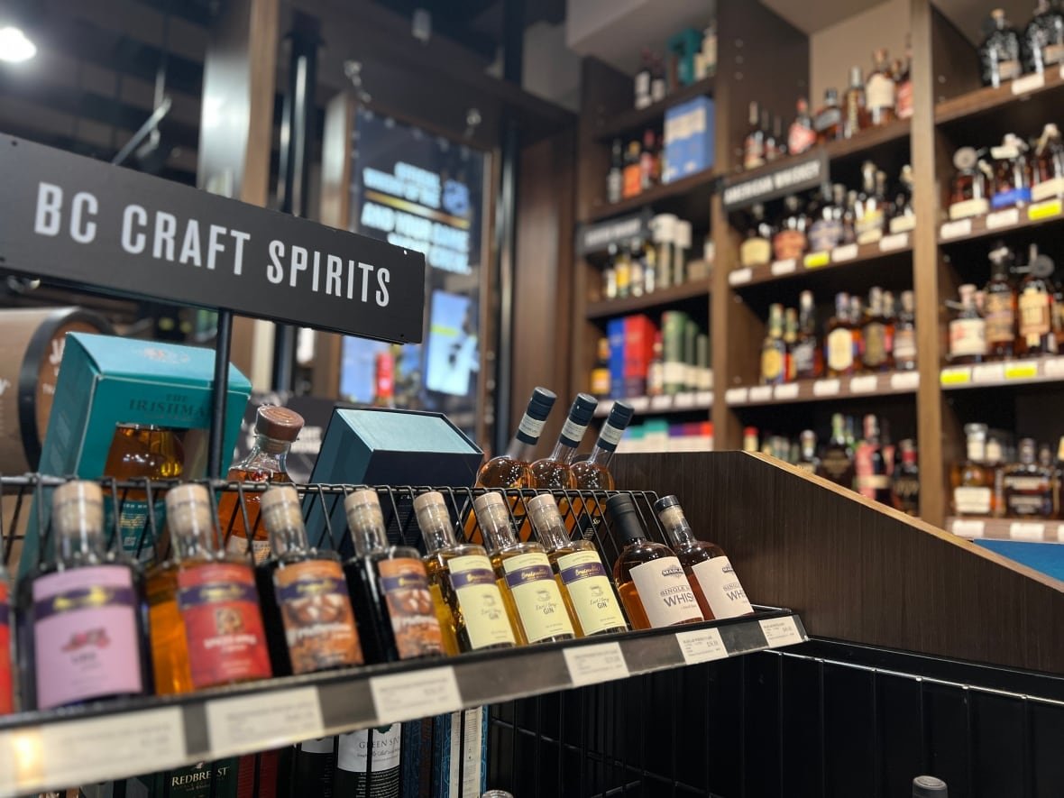 Various liquor bottles are seen on store shelves. A display rack in the foreground says 'B.C. craft spirits.'