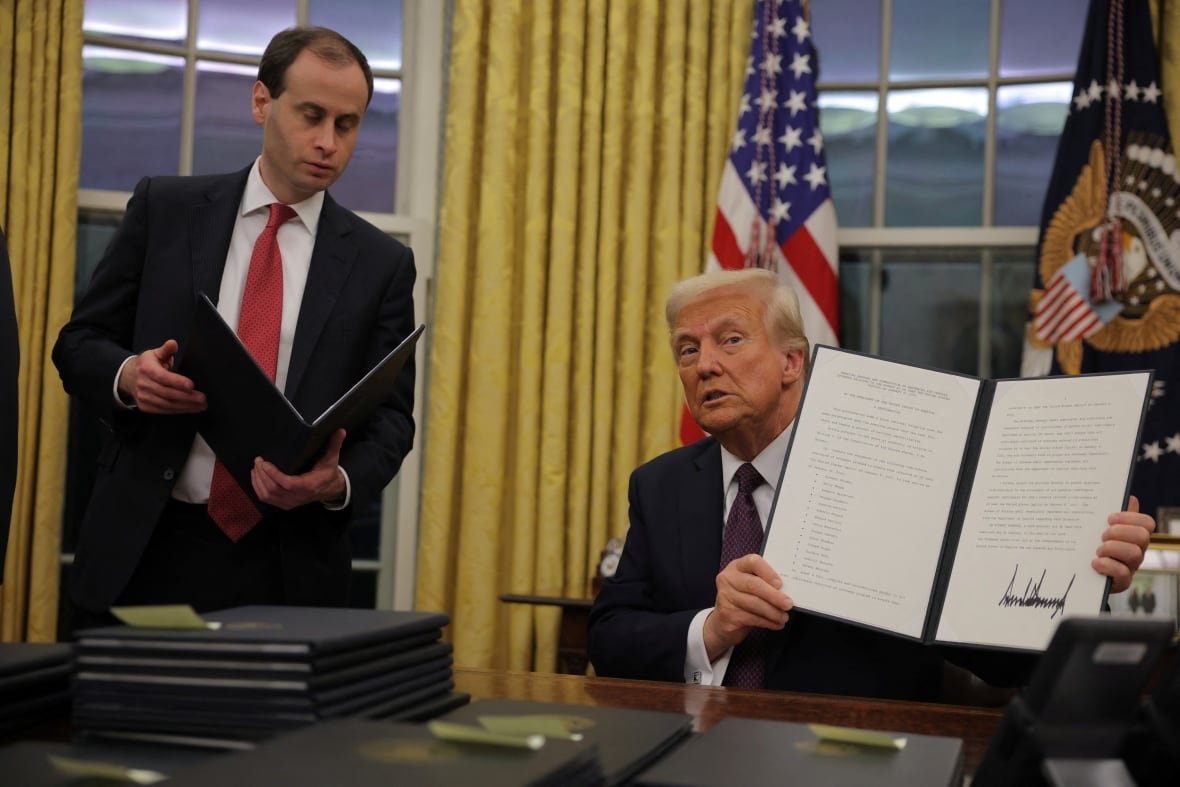 U.S. President Donald Trump holds up an order he signed to pardon certain Jan. 6 defendants.