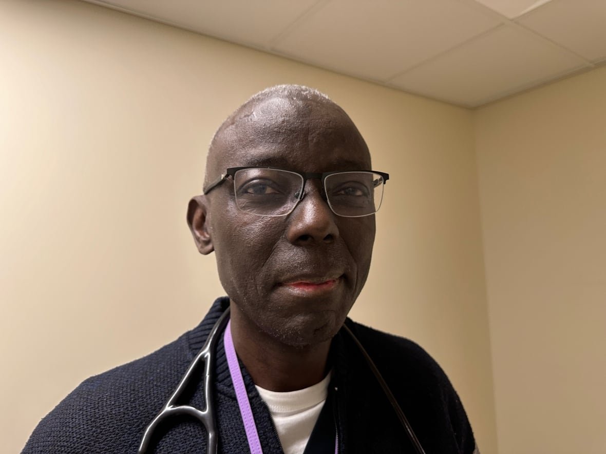 A solemn man with glasses and a stethoscope around his neck and a few silver hairs