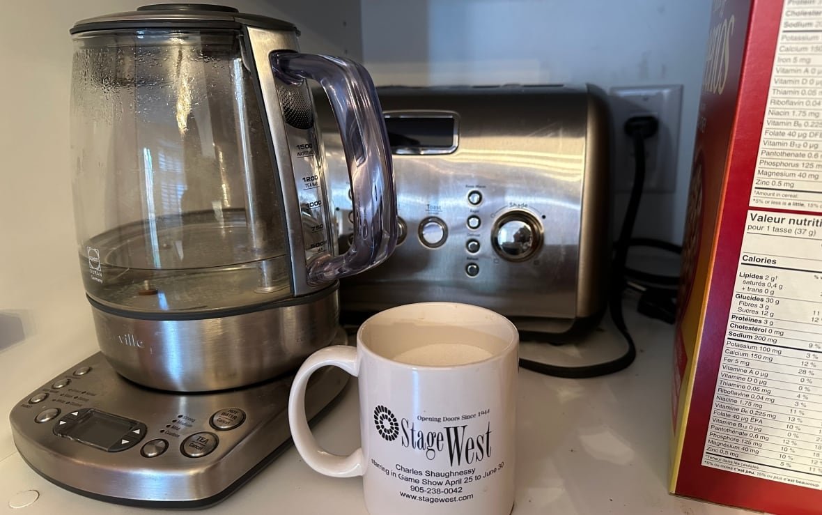 A kettle and toaster instide a cupboard which contains an internal electrical outlet. 