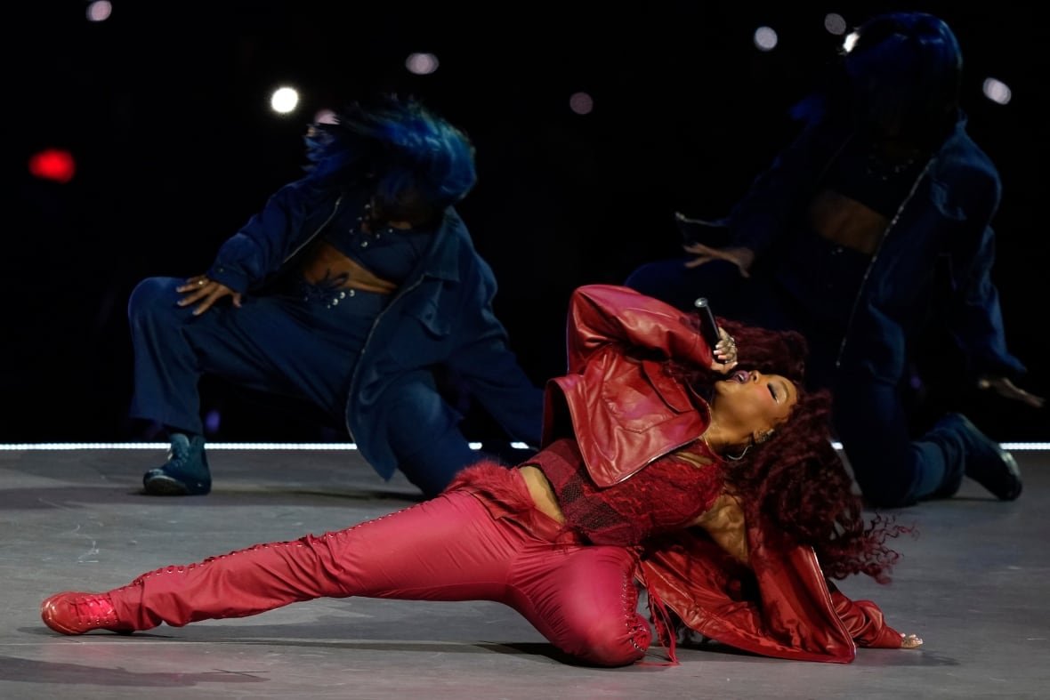A singer and other performers dance onstage.