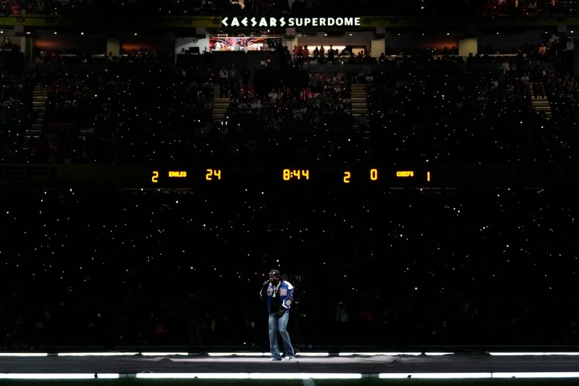 A rapper performs onstage inside a packed stadium.