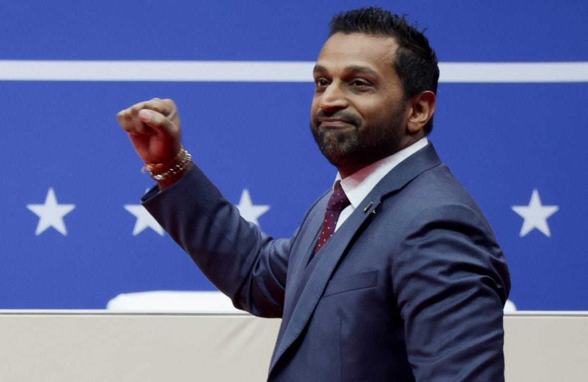 A man raises his fist in front of a stars and stripes background.