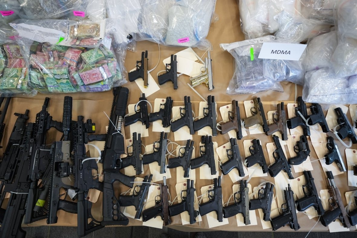 Firearms, illicit drugs and cash that were seized last week are displayed before a news conference at RCMP headquarters, in Surrey, B.C., on Thursday, October 31, 2024.