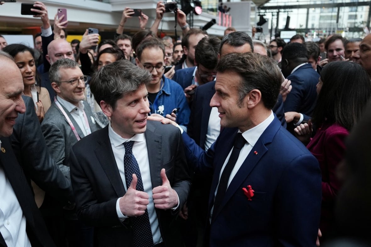 Two men wearing suits are shown speaking to each other in a crowd.
