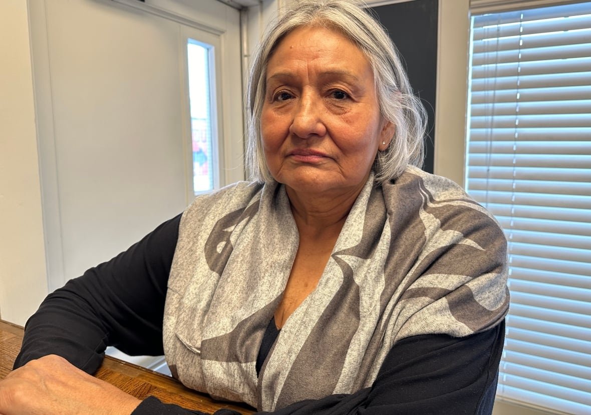 A woman with grey hair looks into the camera. 