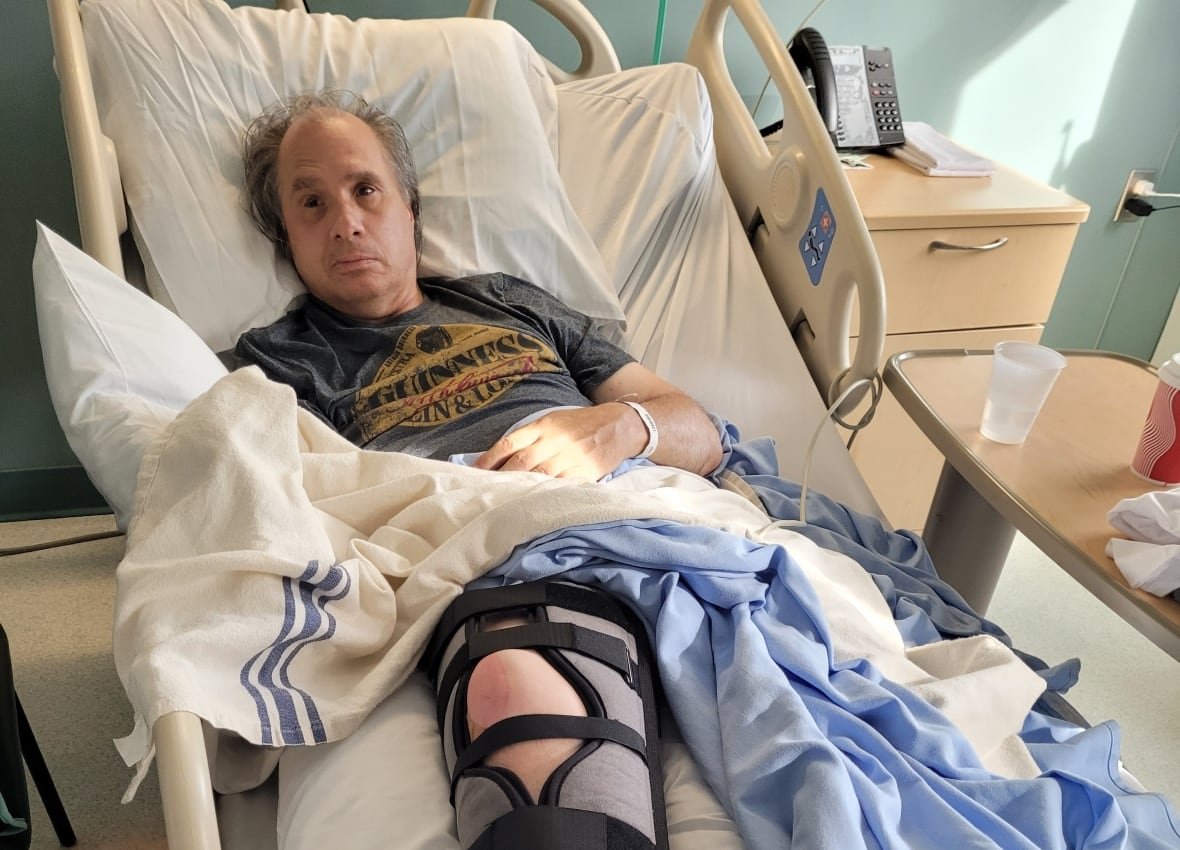 A man in a hospital bed wearing a knee brace.