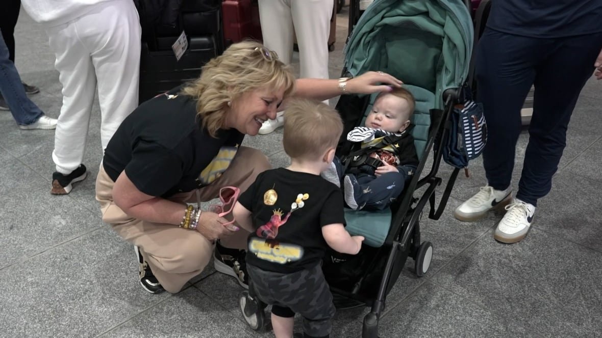 A woman crouches over two children in an airport