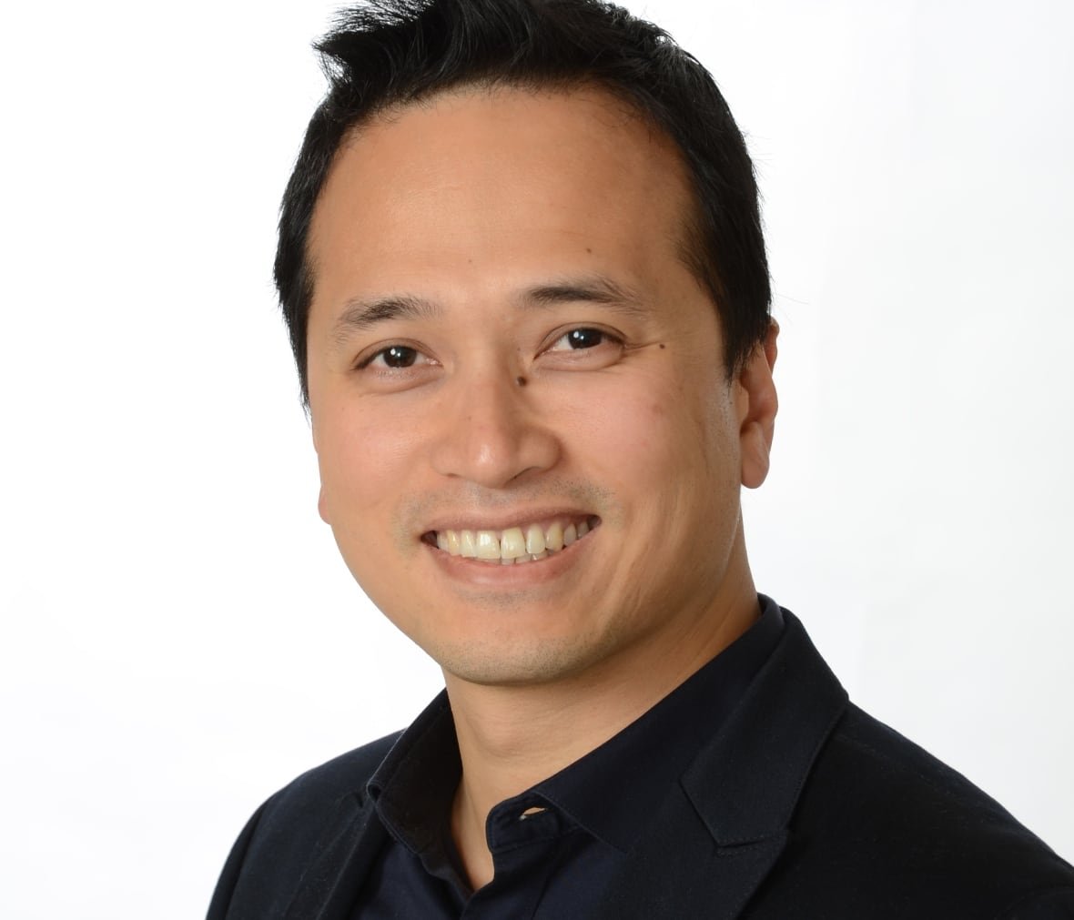 A headshot of a man wearing a black shirt. 