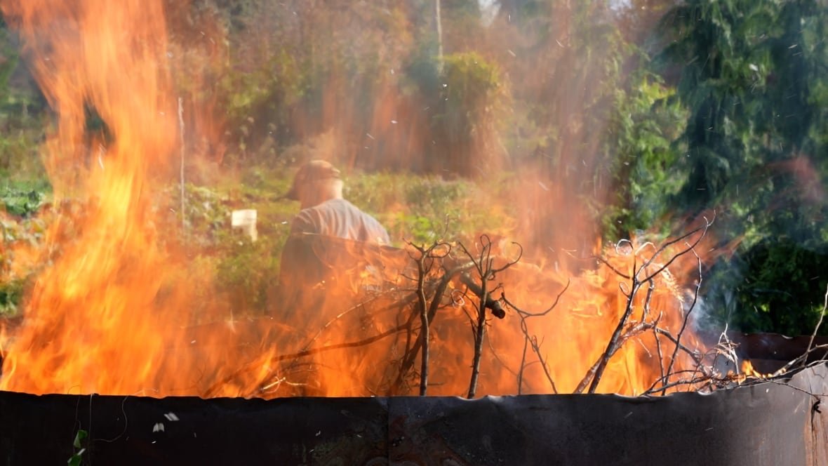 Fire reaches over the top of a kiln.