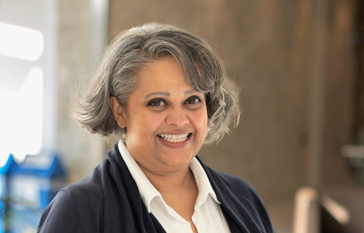 A woman with a short, grey bob smiles while posing for a portrait. 