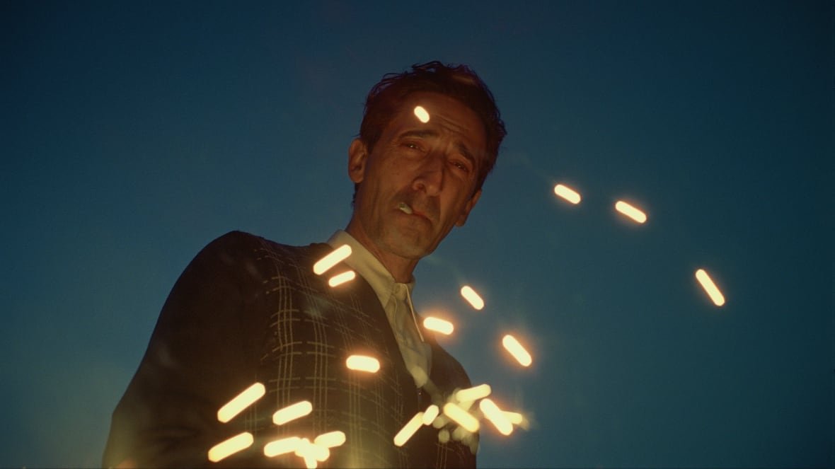 Adrien Brody smoking a cigarette in the film, The Brutalist. 