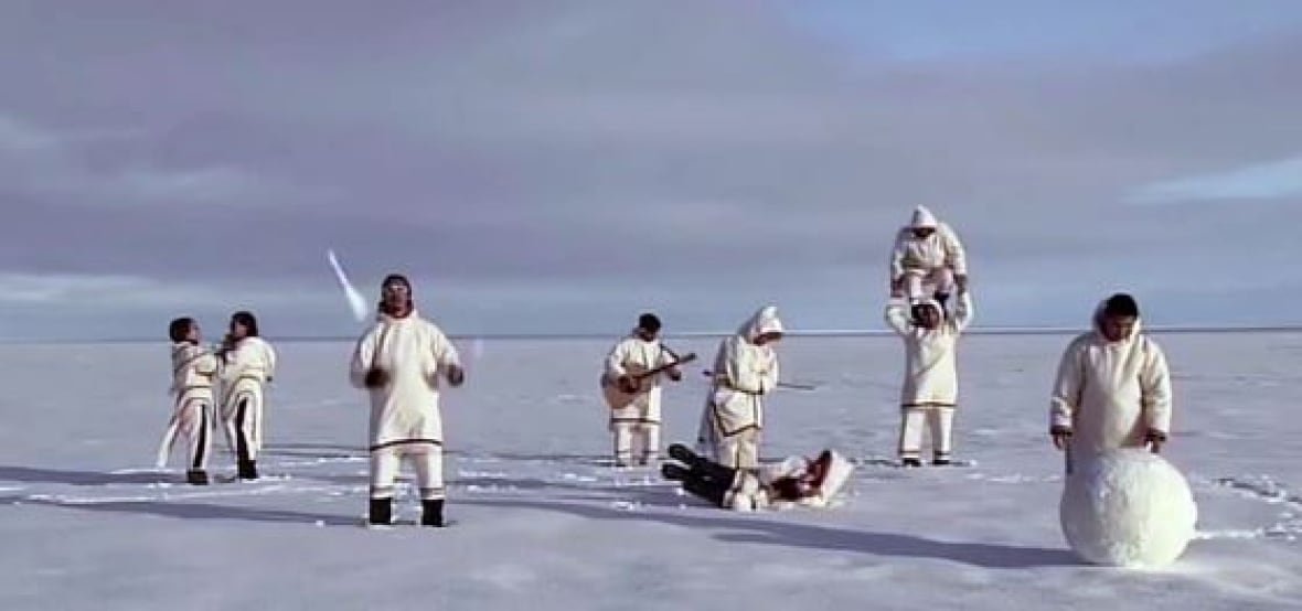 A group of people dressed in traditional Inuit gear performing on the tundra 