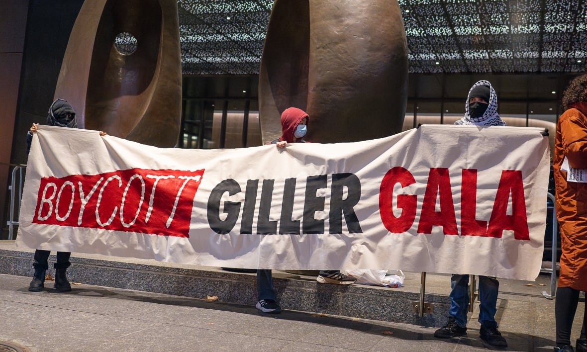 People hold up a giant banner that says Boycott Giller Gala. 