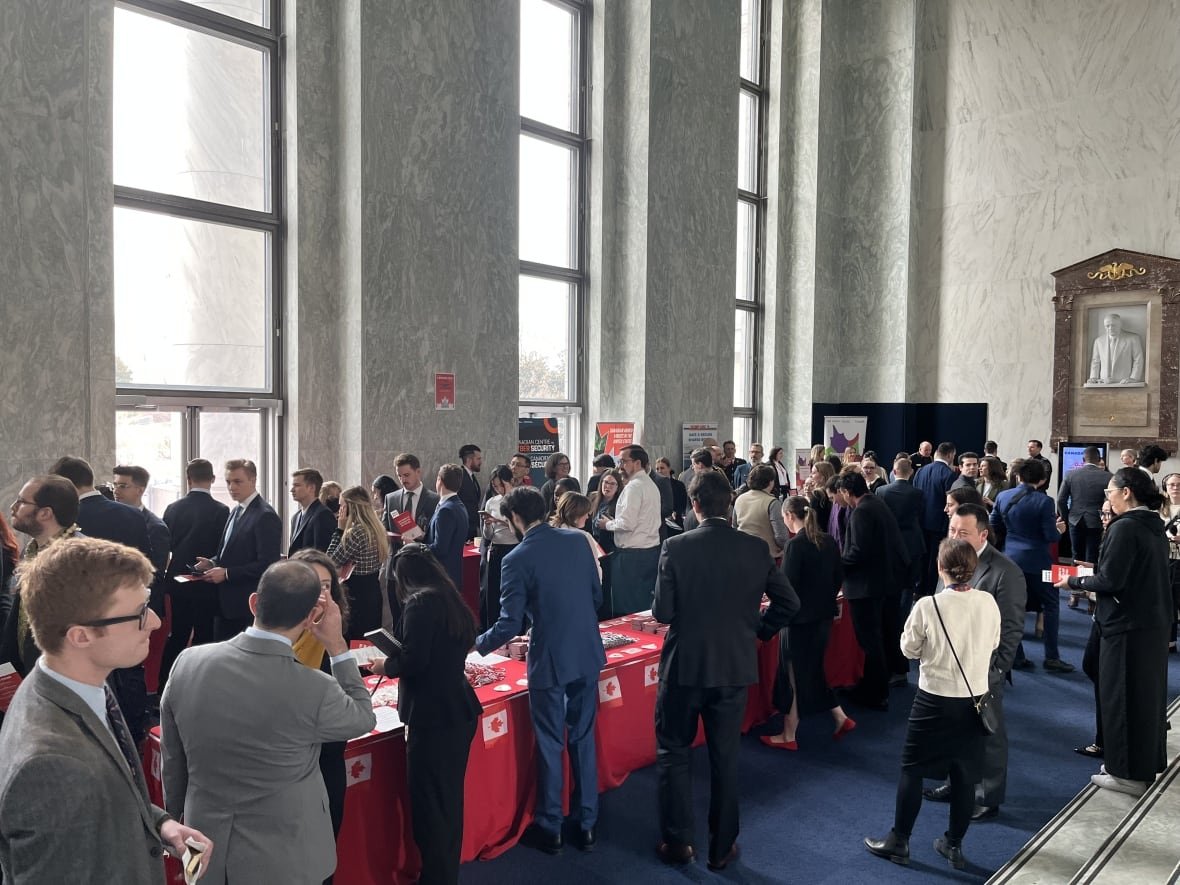 Dozens of people gather around red tables with Canada merchandise.