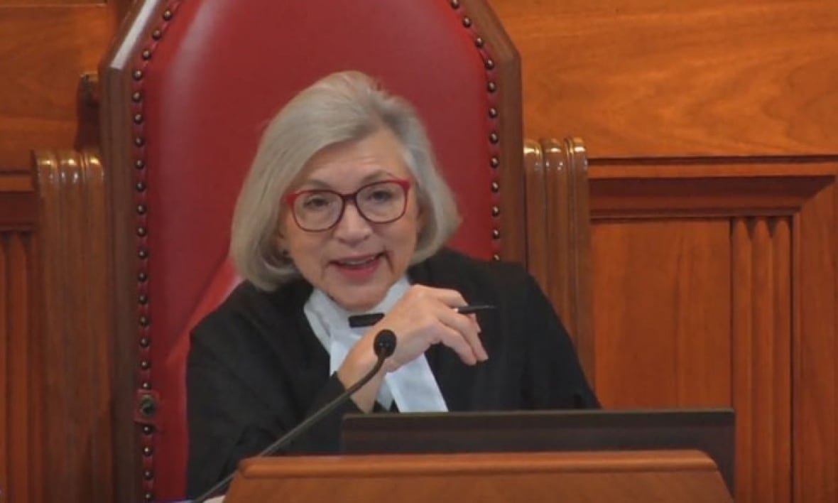A woman in judges robes speaking into a microphone. 