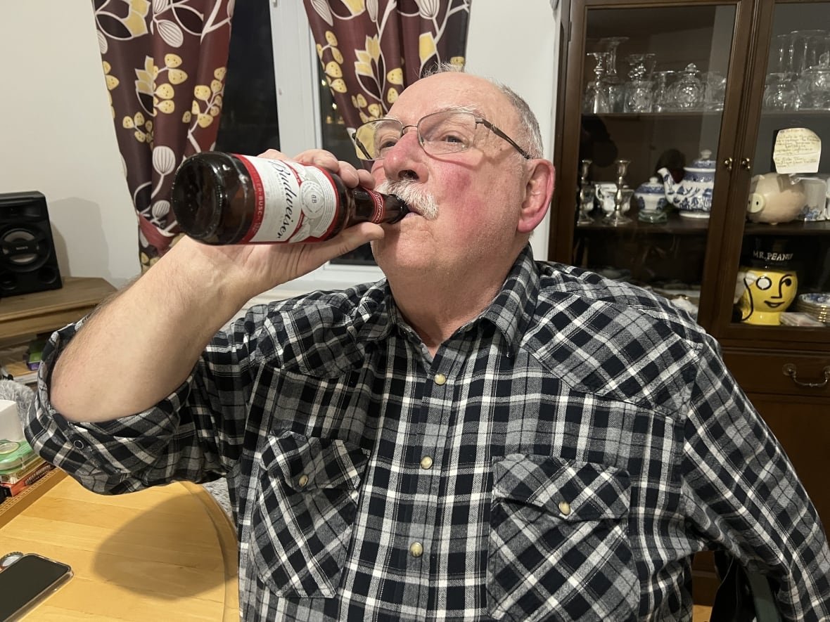 A man drinks from a bottle of beer. 