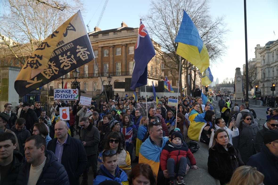 People in a crowd gather on the street and hold flags.