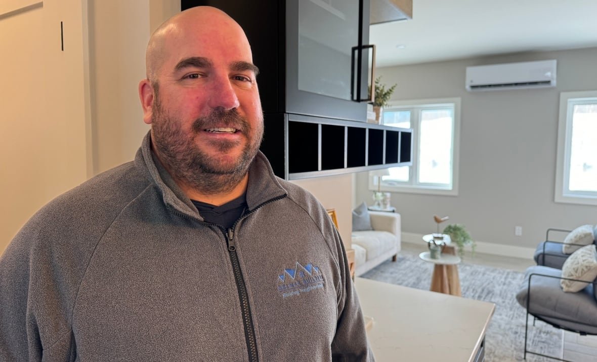 A man with a beard stands in a nice new house