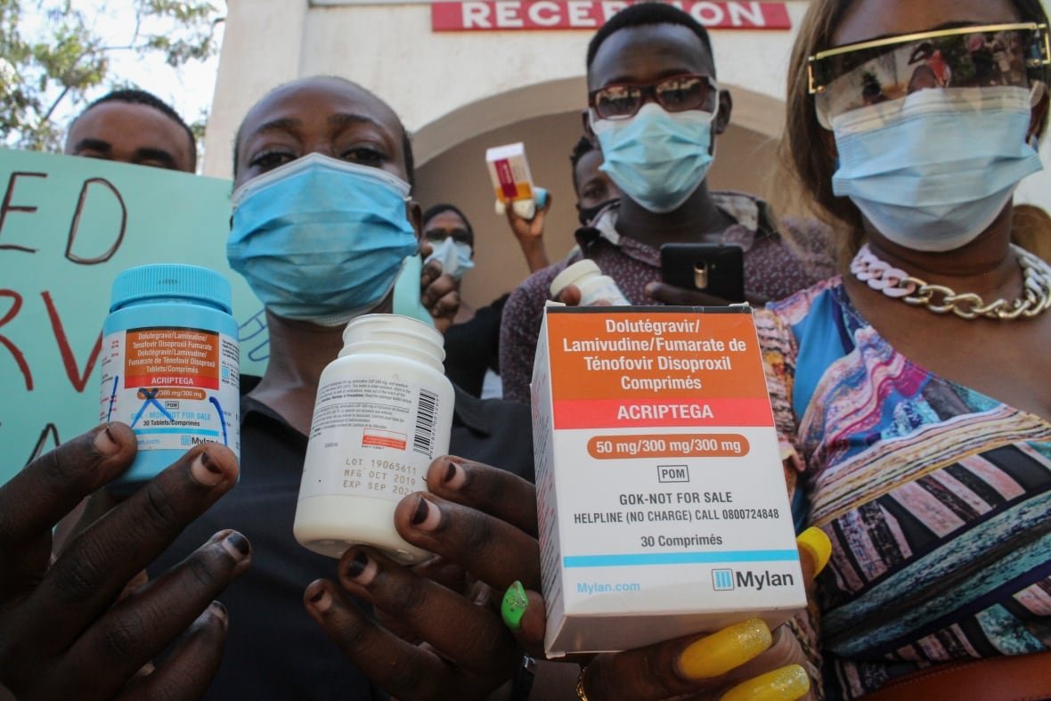 People in masks hold boxes of medications