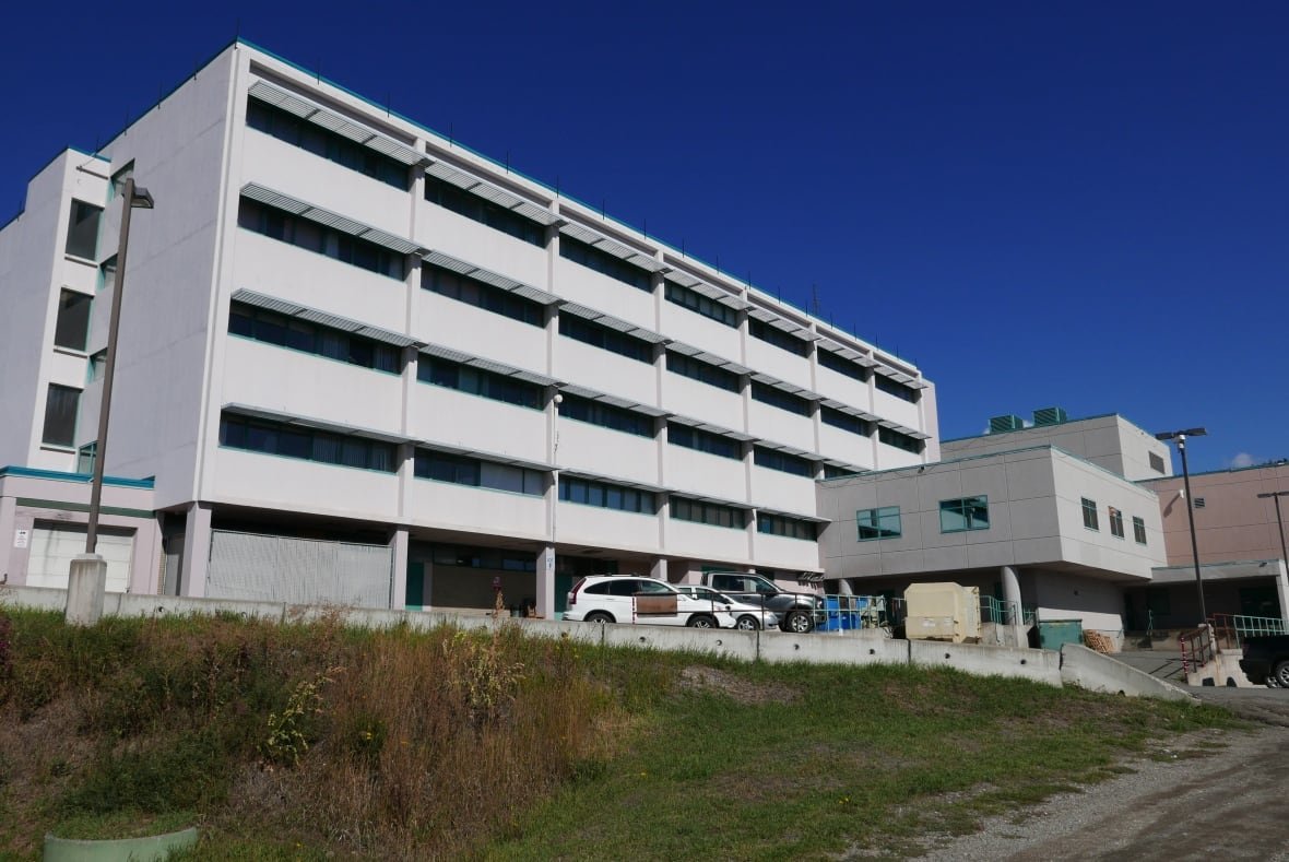 White rectangular building with cars out front.