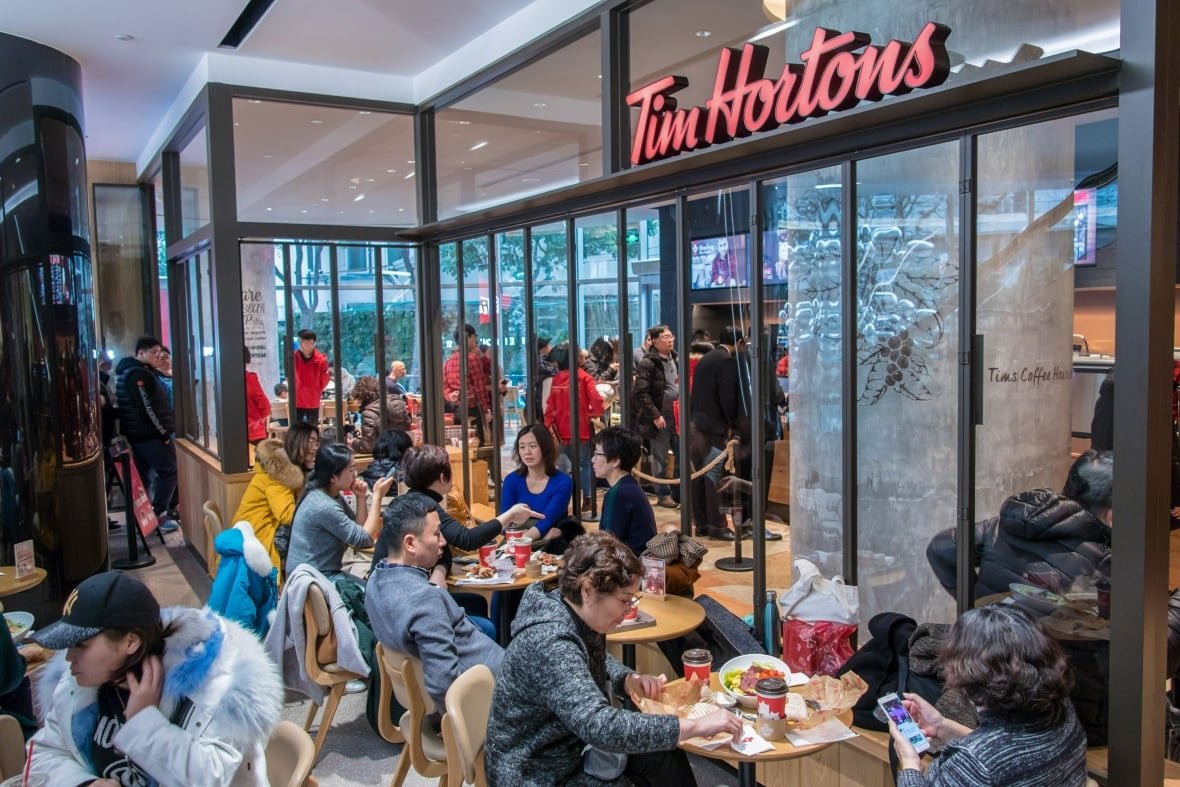 All the seats are filled with people and there's a long line of people at the counter waiting to order at a Tim Hortons store in Shanghai, China.