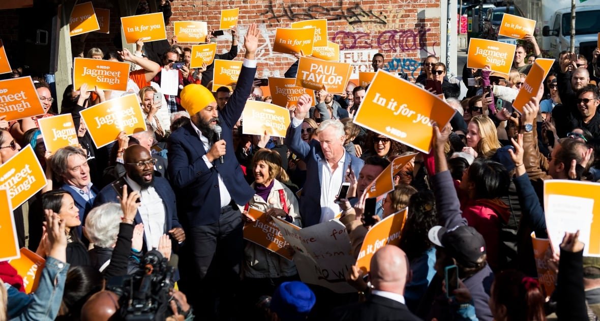 NDP leader Jagmeet Singh is surrounded by a crowd of supporters in Toronto holding orange signs.