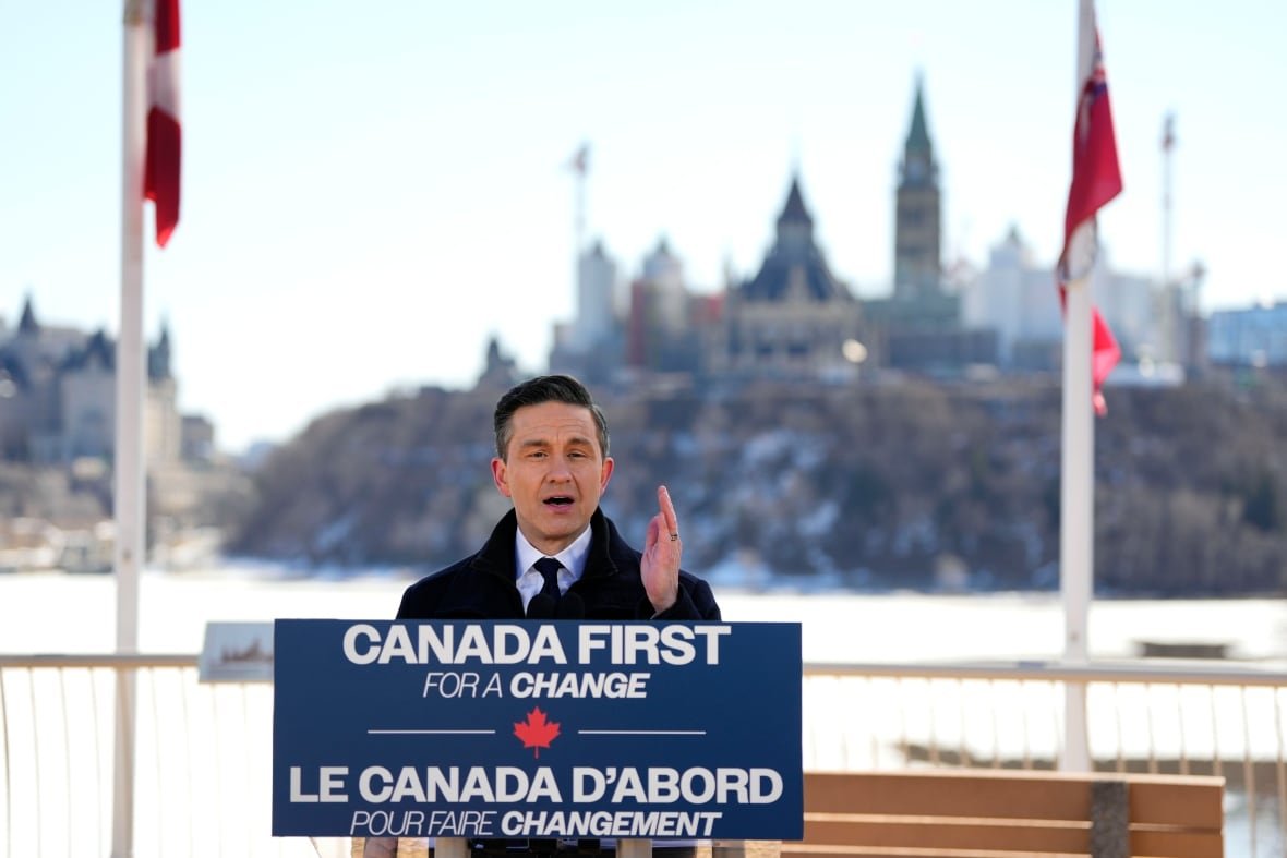 A person gestures while speaking at an outdoor lectern adorned with a sign reading, 'Canada first for a change.'