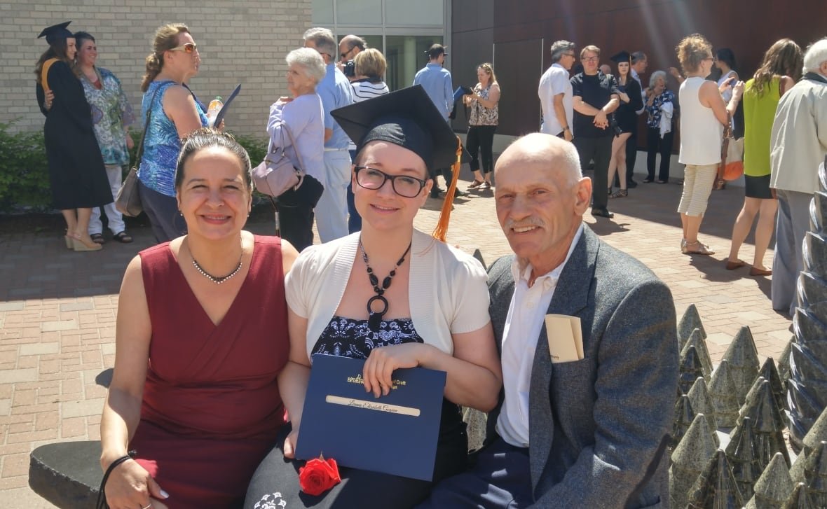 A young graduate sits between a man and a woman.