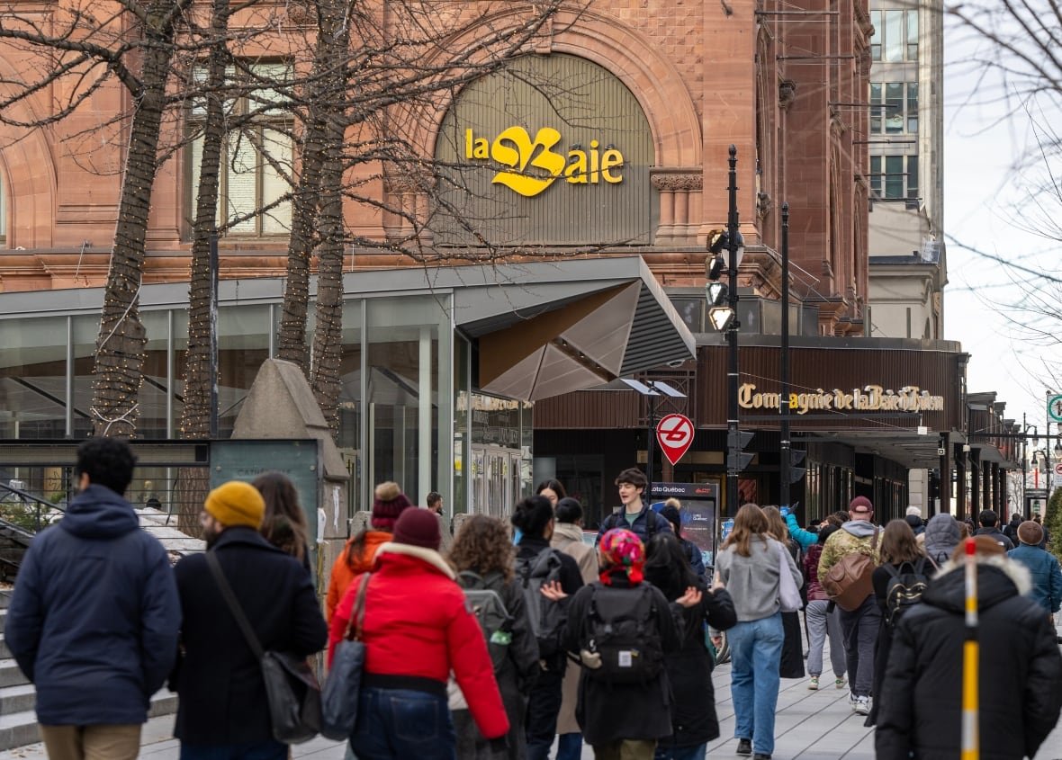 People walk down a sidewalk near a department store.