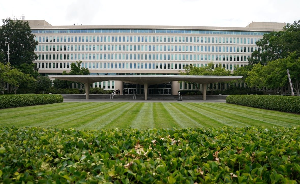 A large building is seen beyond a vast lawn.